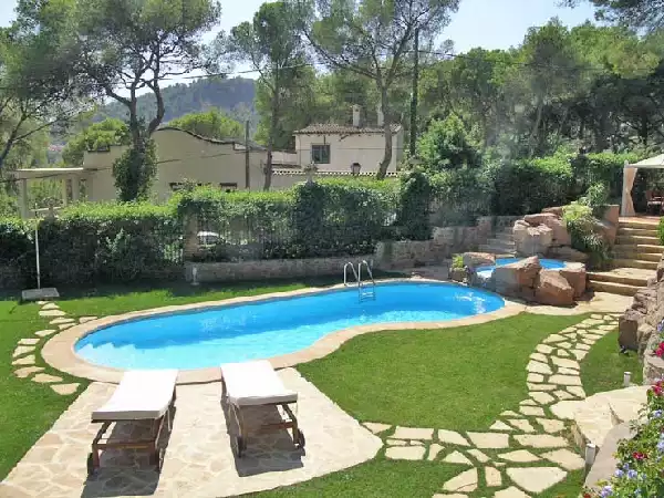 Piscina forma libera con cascata, area sdraio e rocce finte