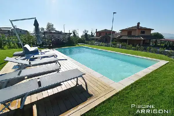 Piscina interrata con bordo perimetrale e solarium in legno