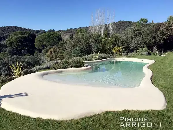 Piscina stile laghetto con rivestimento in sabbia e ampia spiaggia