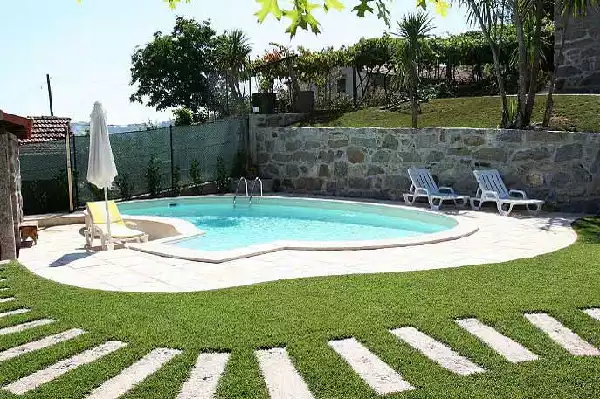 Piscina a forma libera con giardino attrezzato di camminamento in pietra